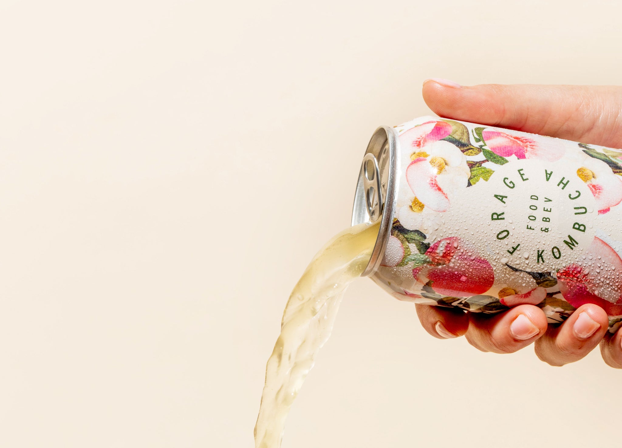 A can of Forage Kombucha being poured out in front of a pale yellow backdrop.
